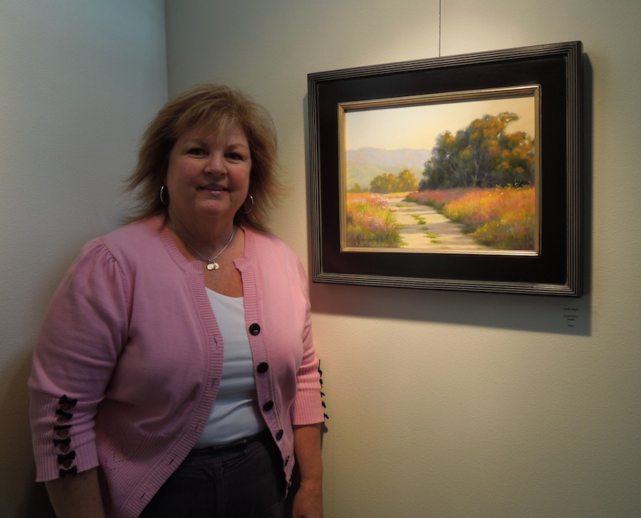 Linda Mutti stands beside one of her paintings at Studios on the Park
